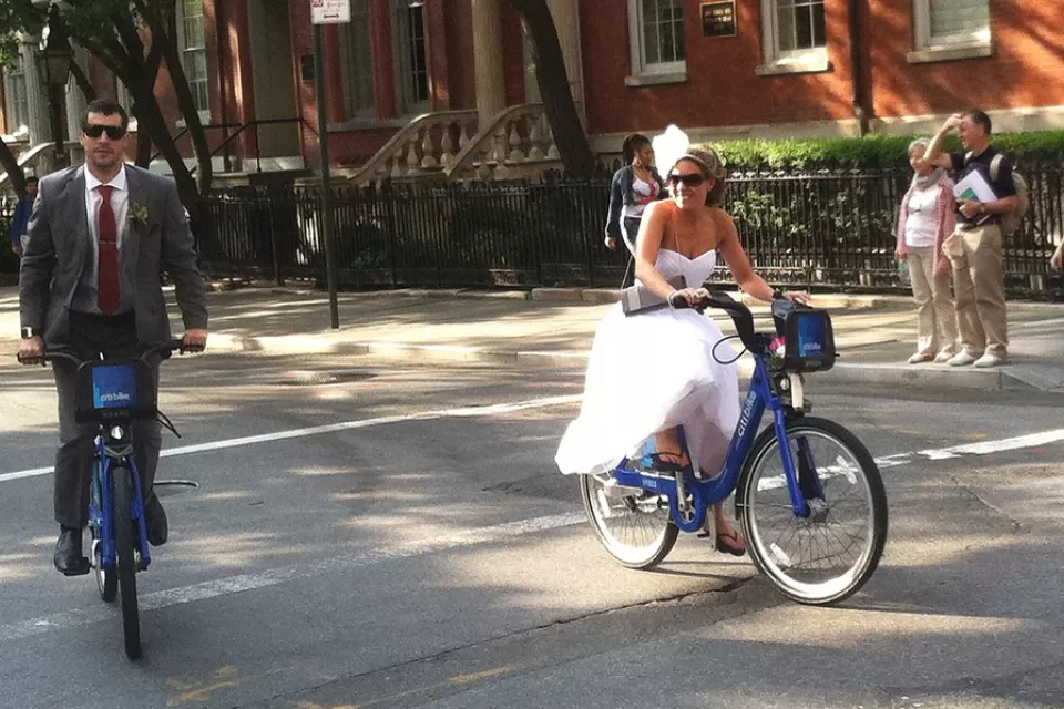 A bride and groom riding on citi bikes in New York